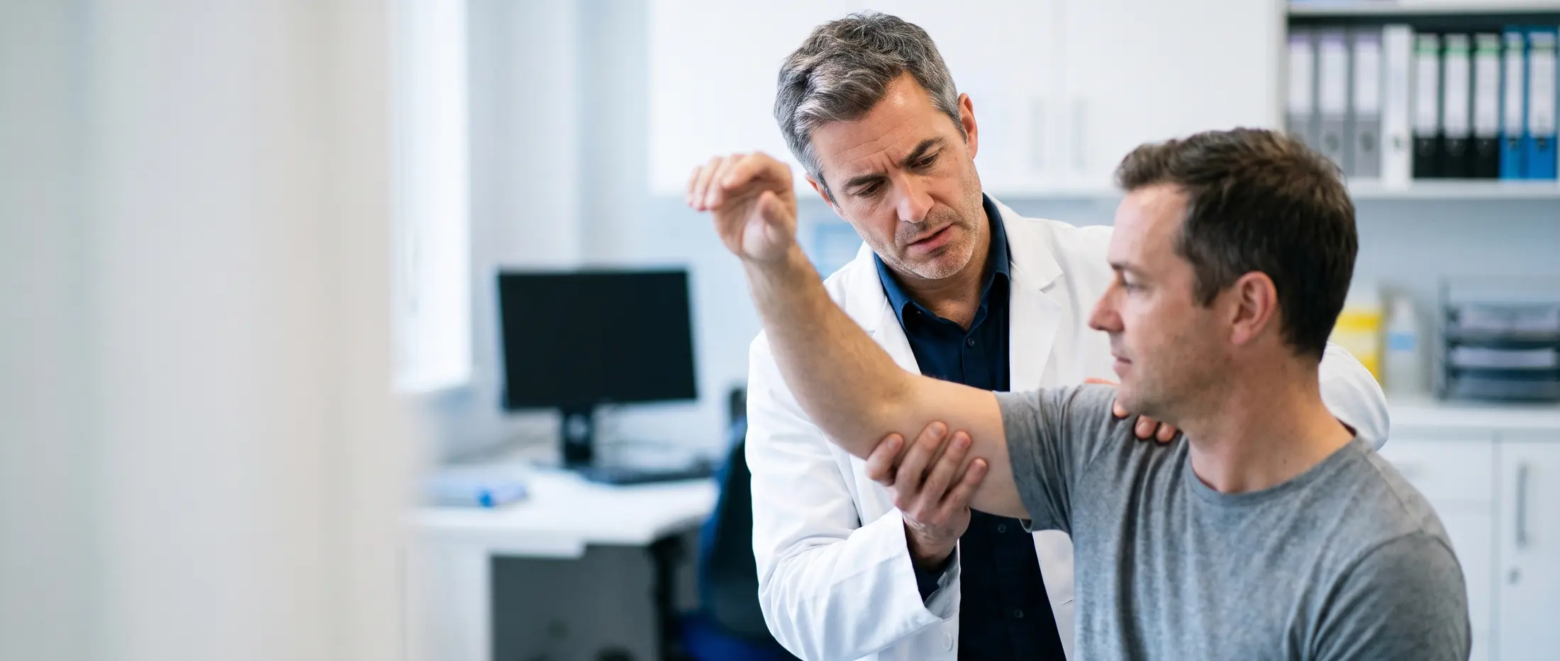 Independent medical expert assessing a claimant's shoulder movement during a medico-legal examination
